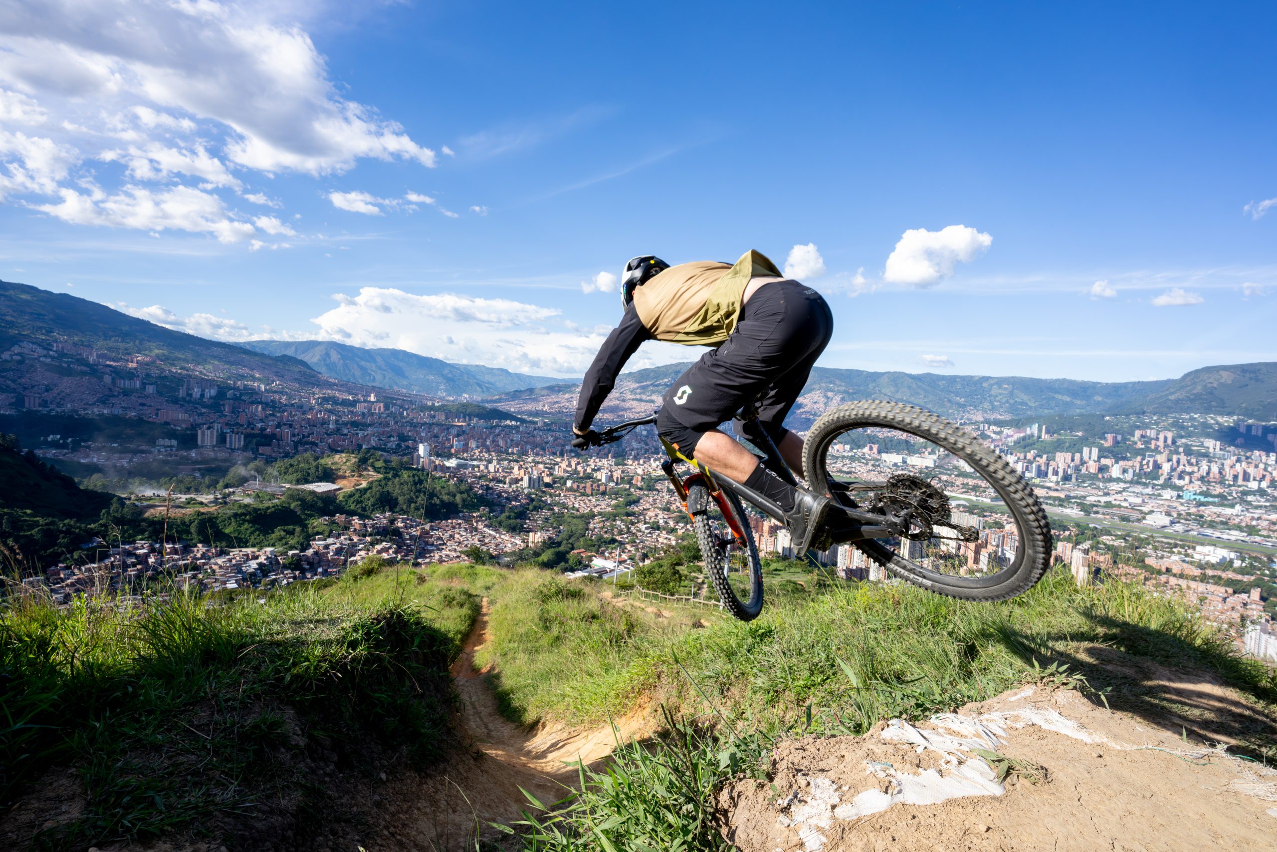 Mountain biker riding a trail overlooking a Colombian cityscape, highlighting the 