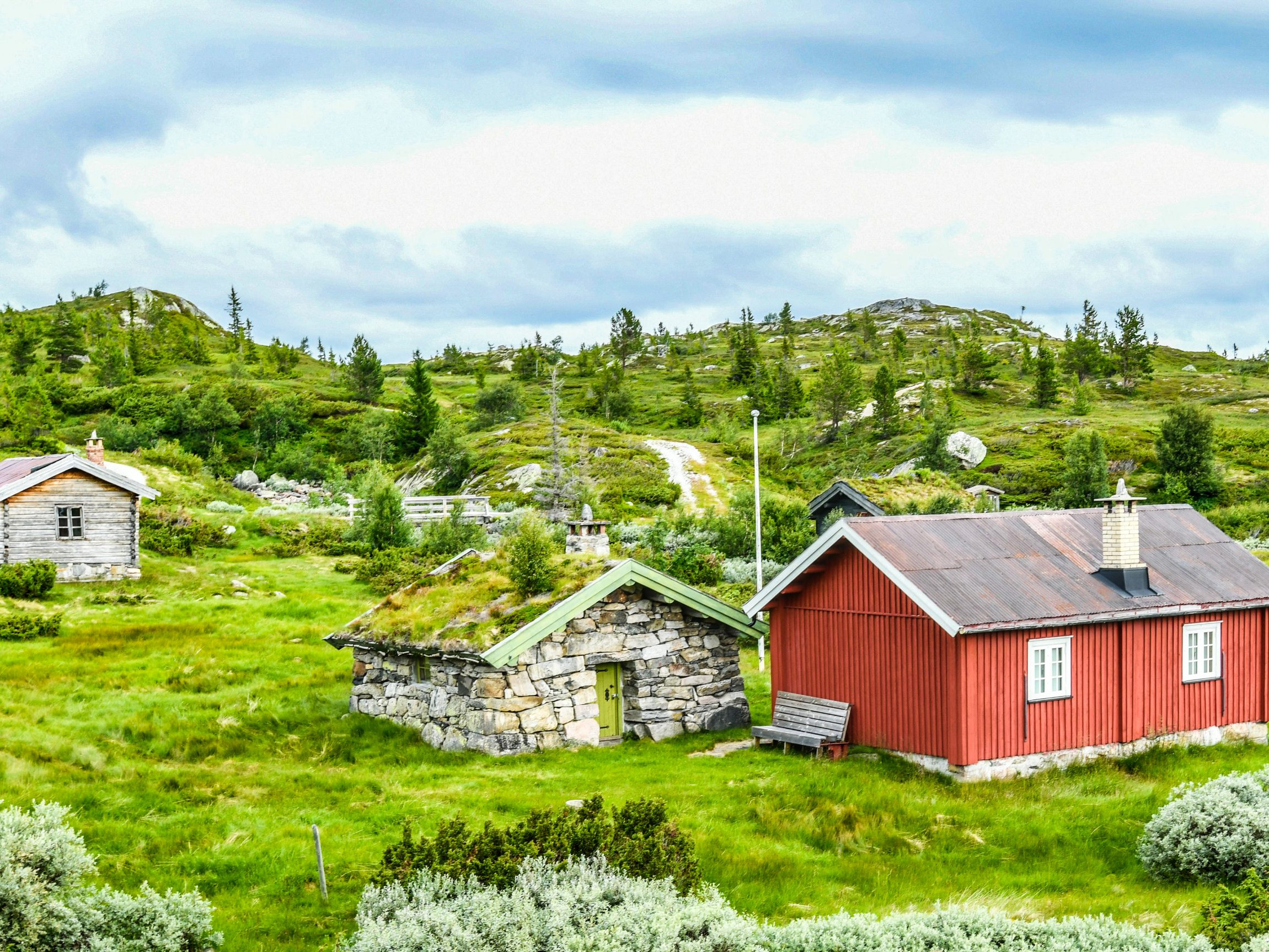Rural cabins in a lush green landscape, symbolizing The Next Frontier exploration theme by Hans Rey. Scenic outdoor setting with greenery. Mountain Bike United.