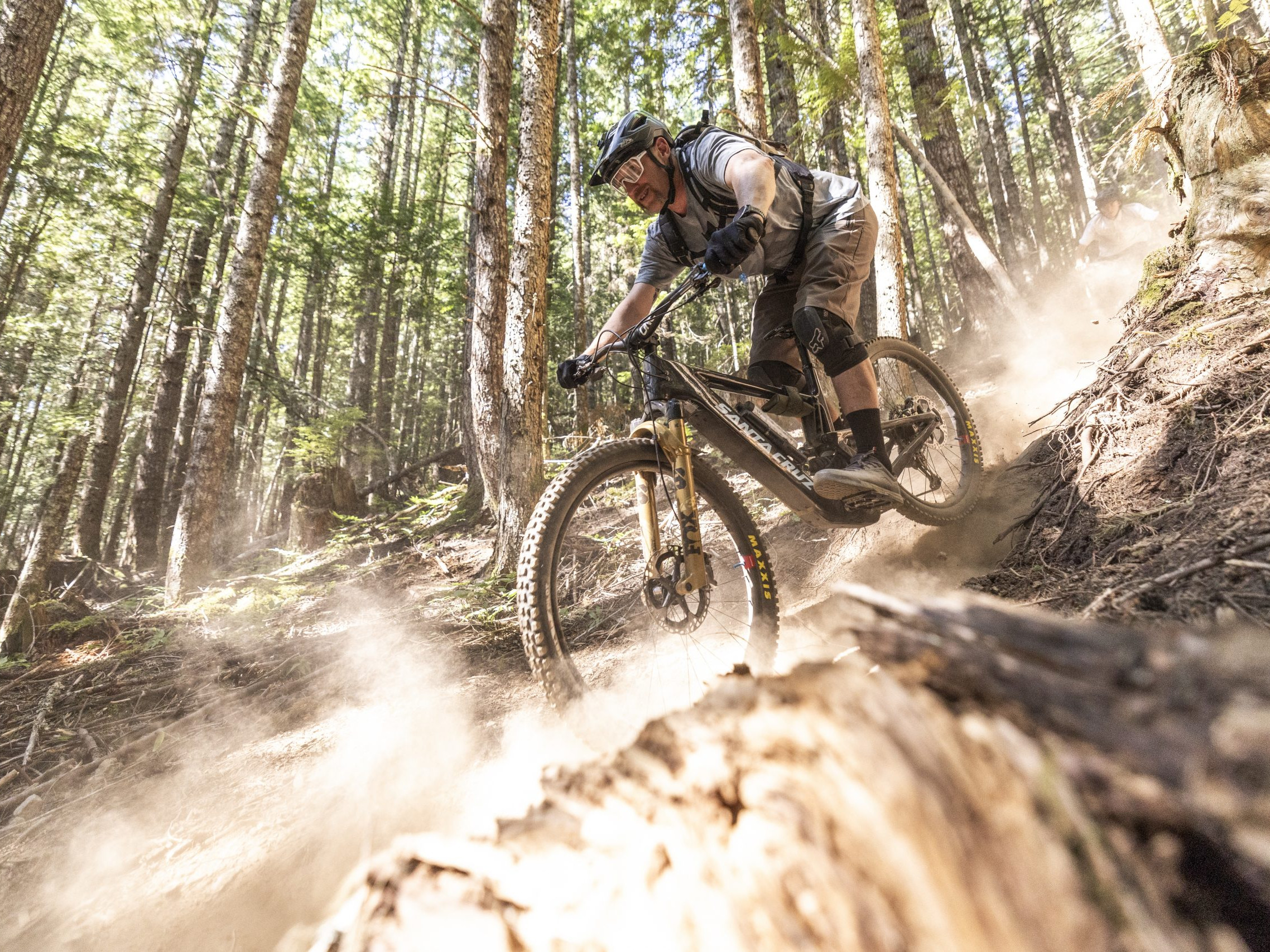 Mountain biker navigating a dusty forest trail, showcasing downhill skills. Related to Hans Rey, highlighting adventure and biking expertise. Mountain Bike United.